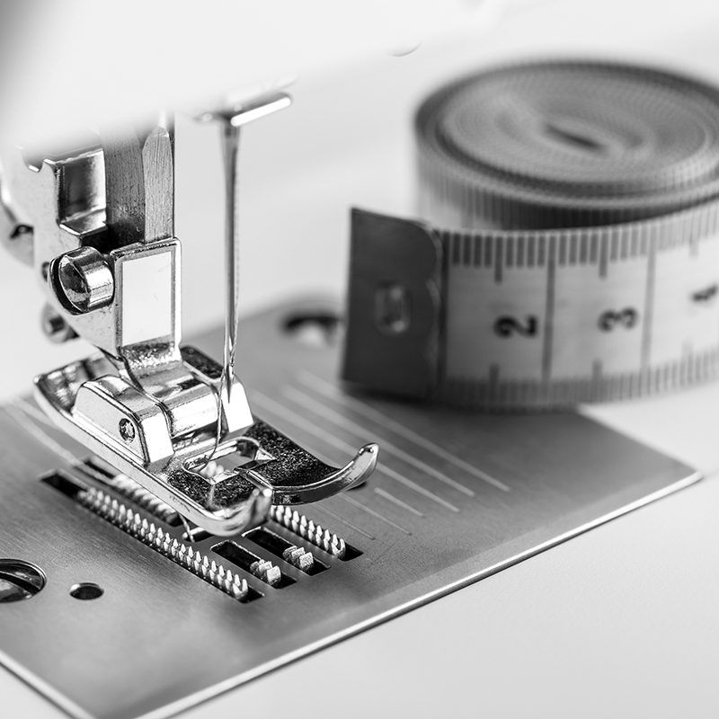 Primer plano de maquina de coser con una cinta métrica en el fondo