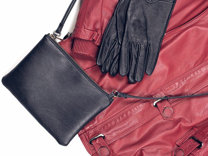 Guantes y bolso negro de cuero junto a una cazadora roja también de cuero.